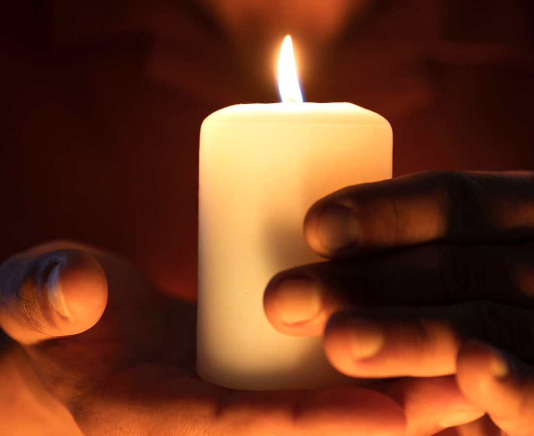Manos sosteniendo una vela encendida