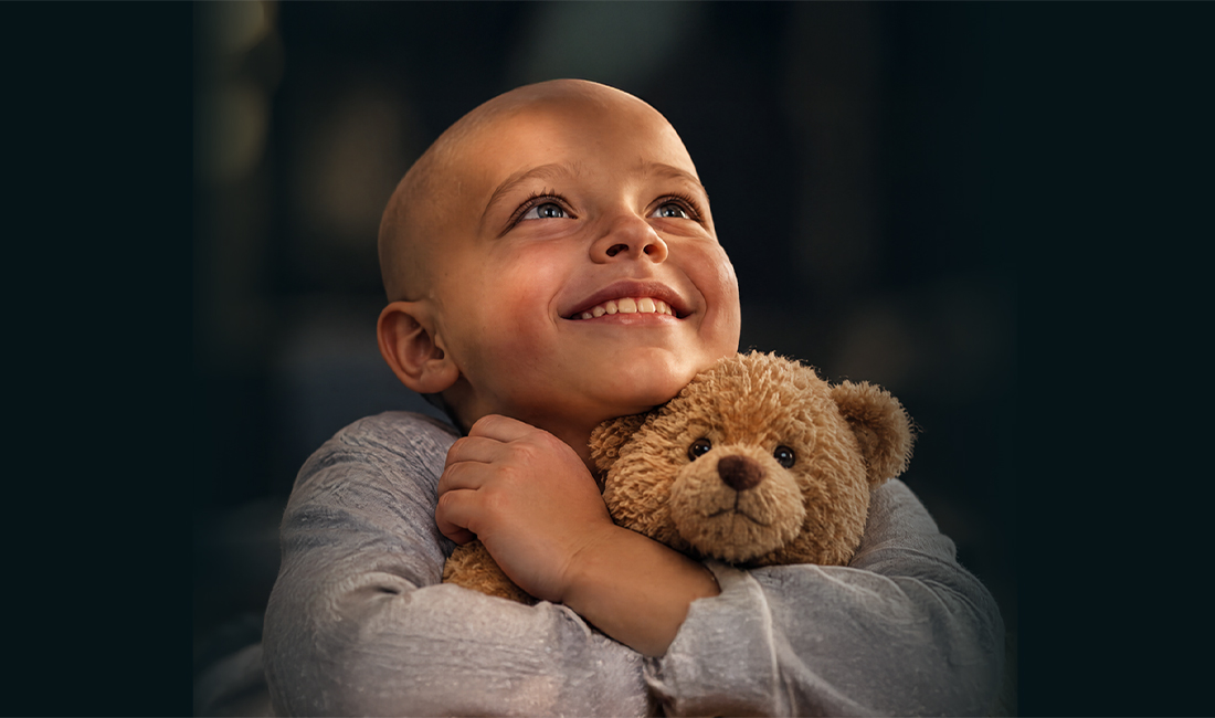 Niño sonriendo mientras abraza un osito de peluche